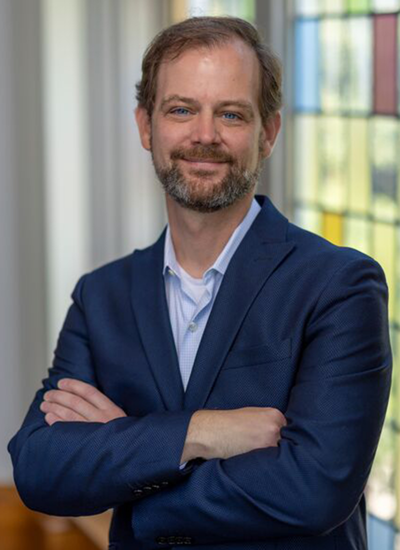 a man with a beard in a blue jacket smiles at the camera