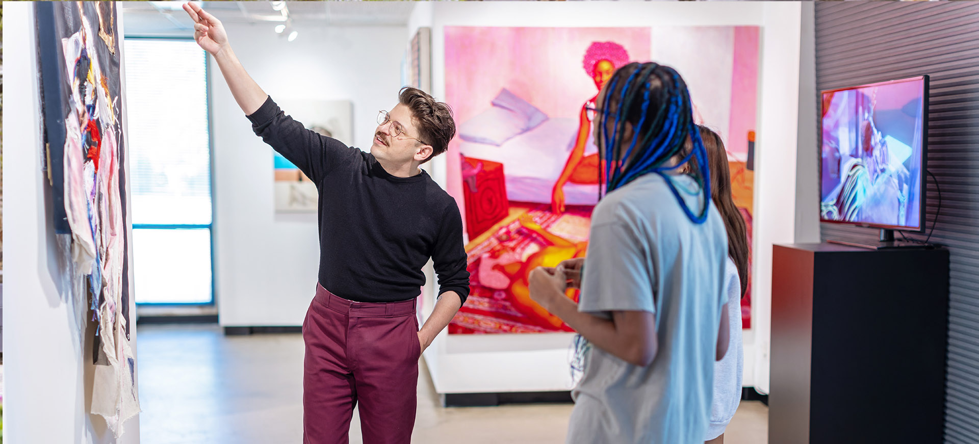 a professor discusses an artwork with students in a gallery