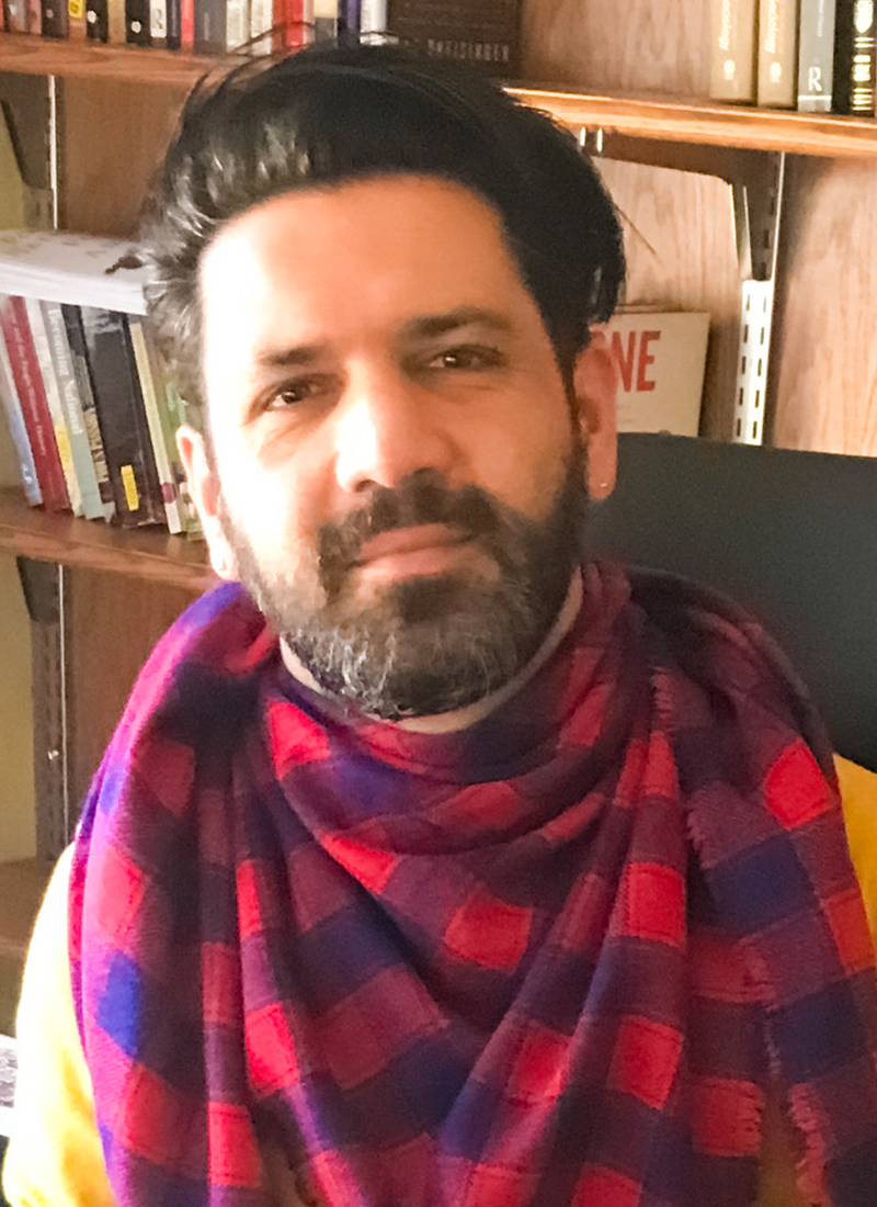 Hadi Khoshneviss, a man with dark hair and a beard wearing a red and blue checked scarf