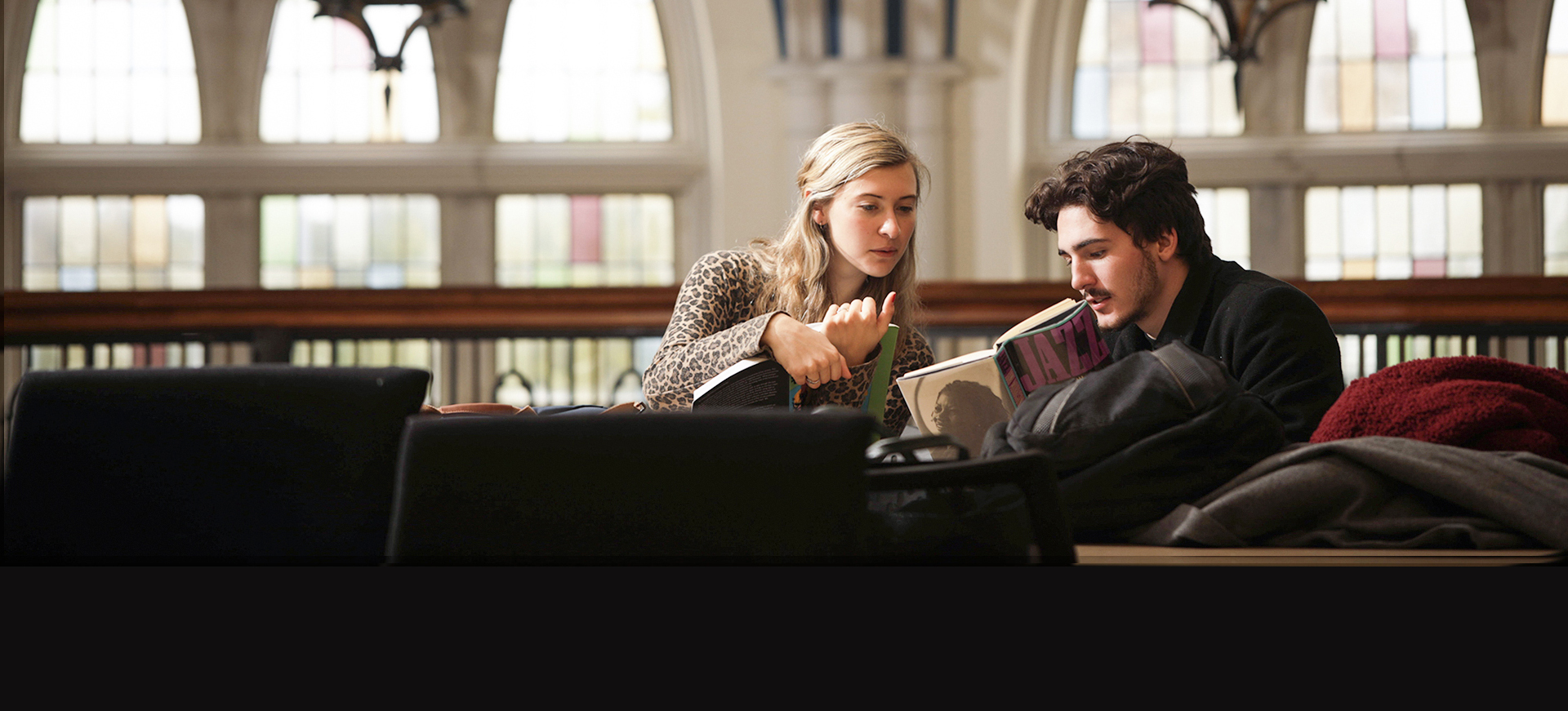 two students confer in the library