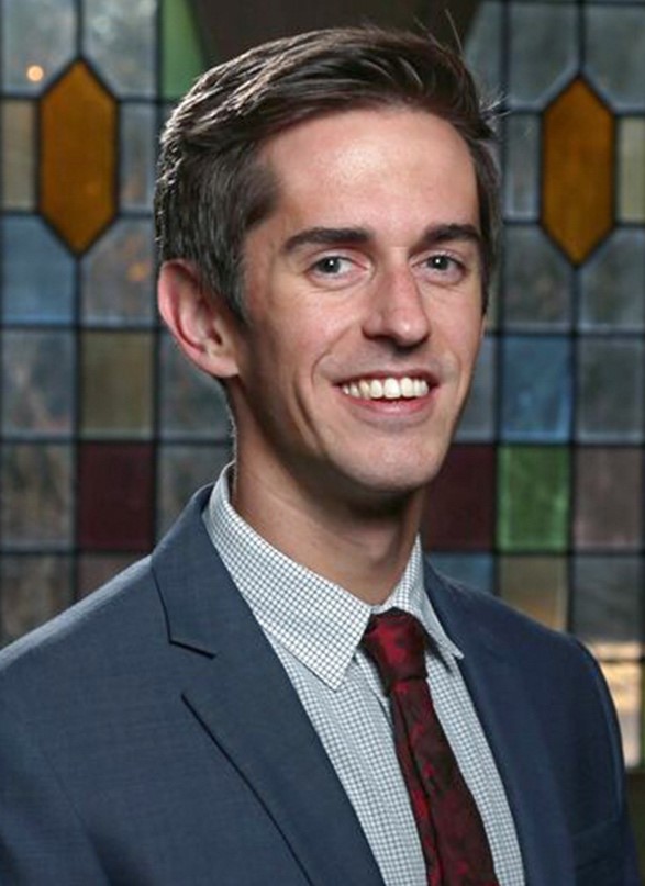 a man in a suite and tie smiles at the camera