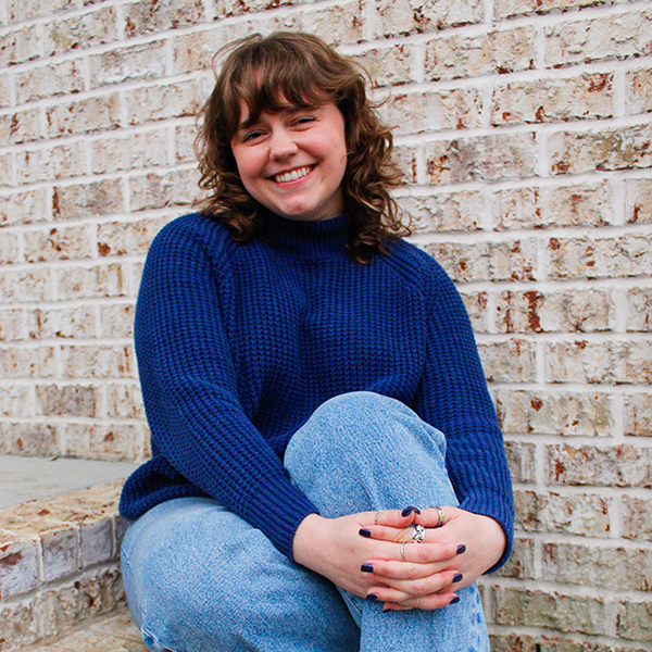 a young woman wearing jeans and a blue sweater