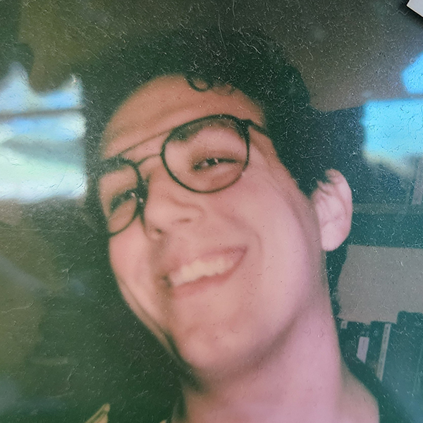 a smiling close-up of a young man with glasses
