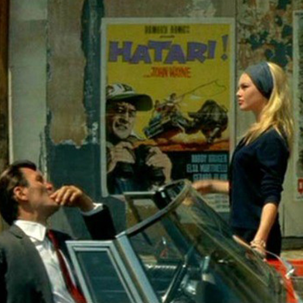 a man in a convertible looks at a woman