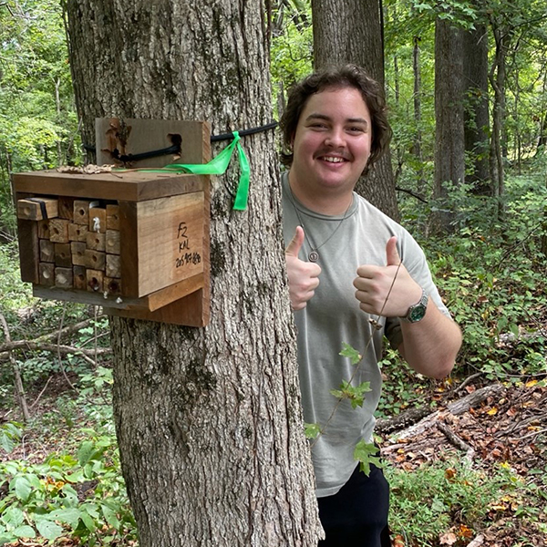 a student with a sample box in the forest