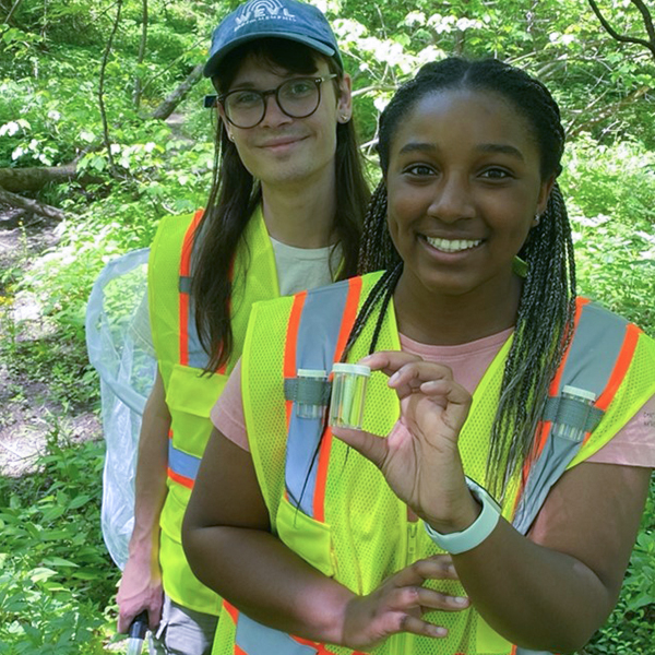 two students take samples in a forest