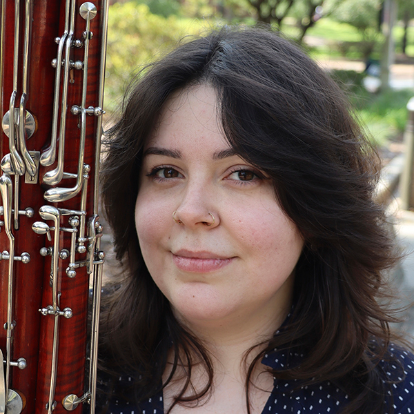 a woman with dark hair holding a bassoon