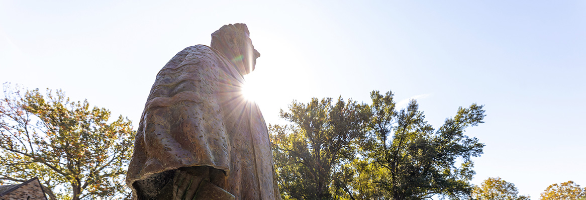 a bronze statue of a man in academic robes