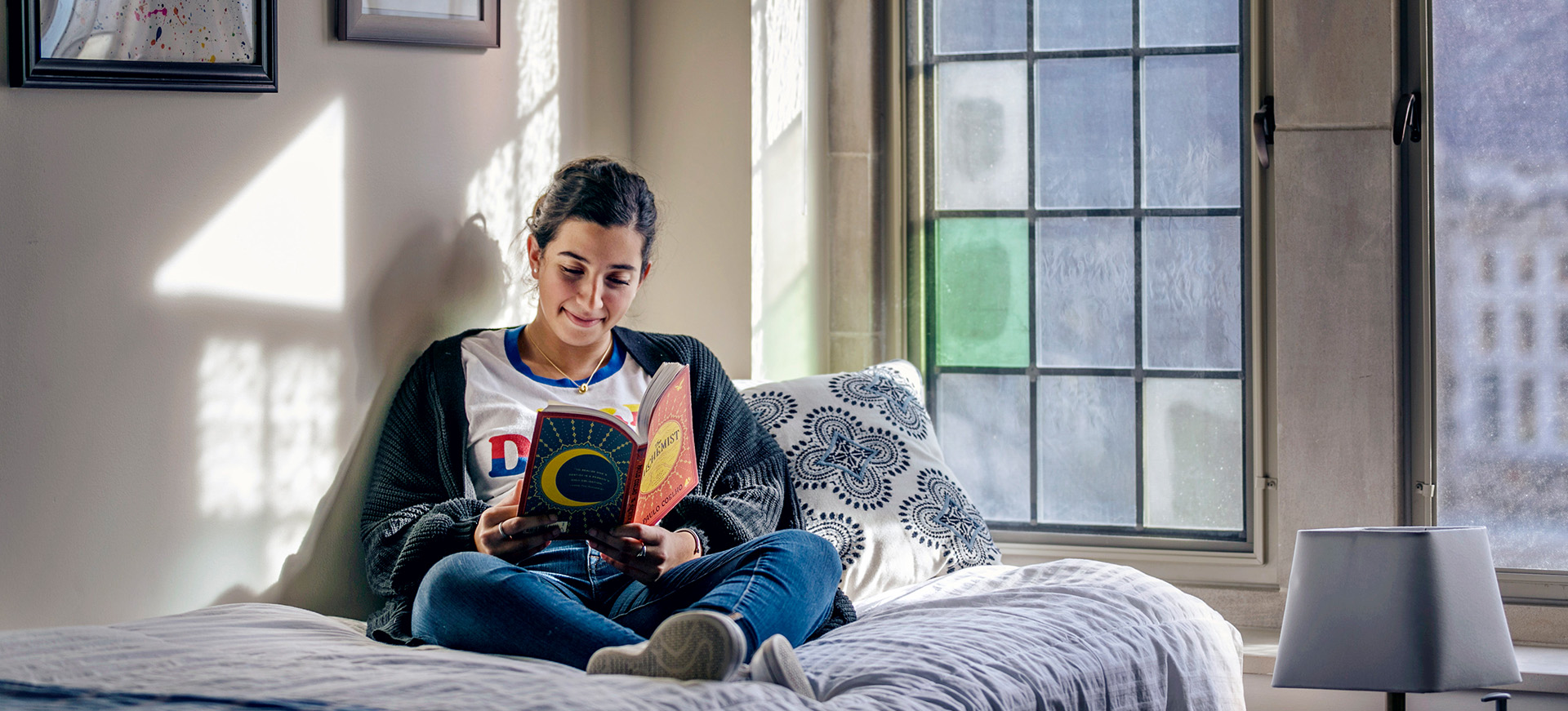a student reading a book in her dorm room