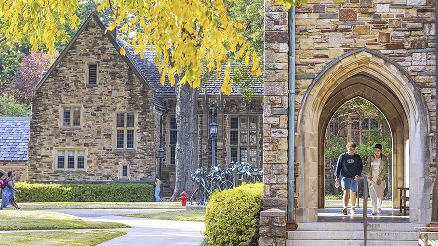 students walk on a campus with Gothic architecture