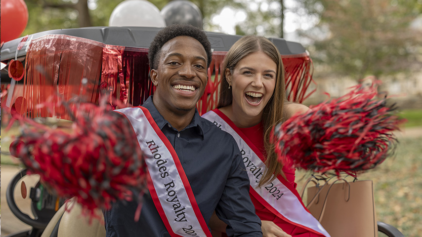 a male and female student cheer with pom poms