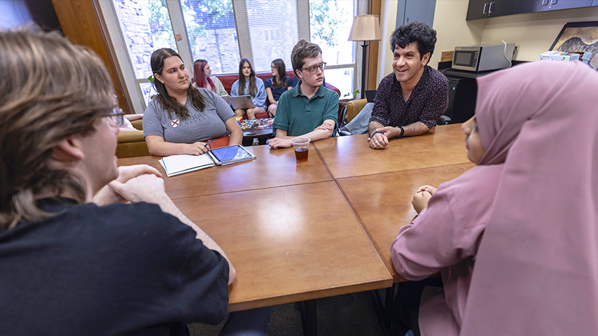 a professor and students talk at a table
