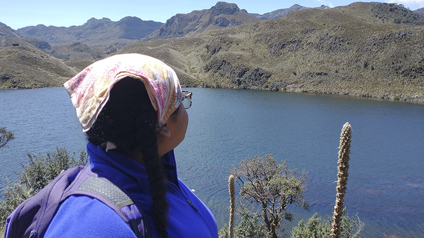 a young woman looks out over a lake surrounded by mountains