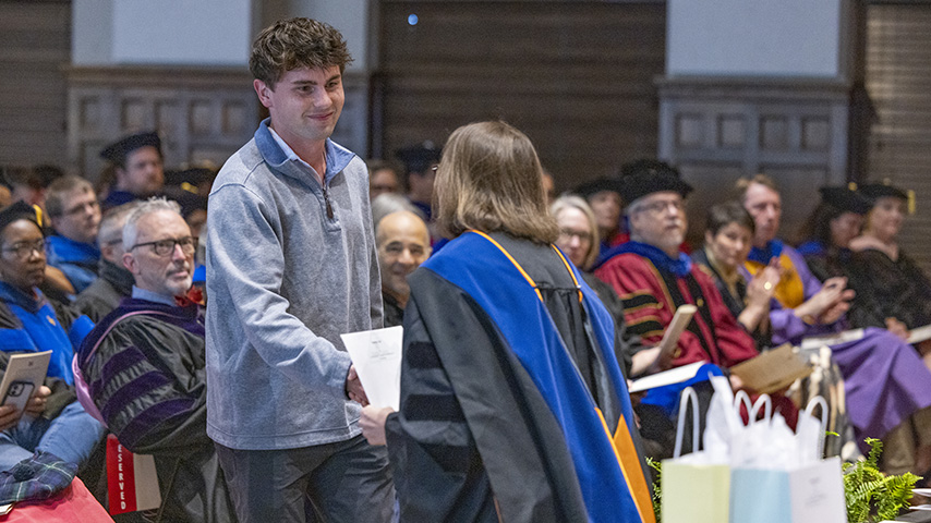 a young man receives an award at a convocation ceremony