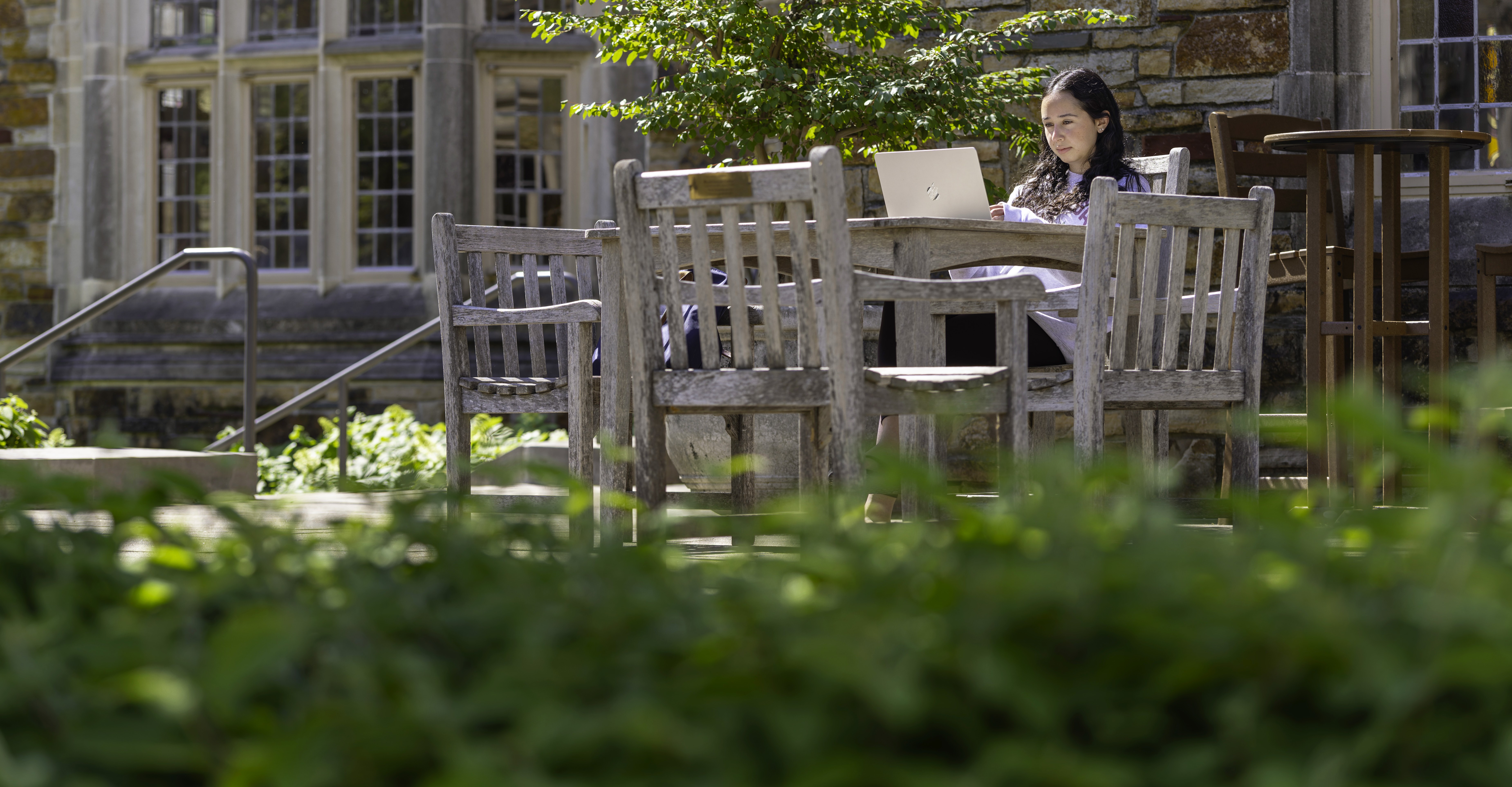 A young woman using her computer outside academic building