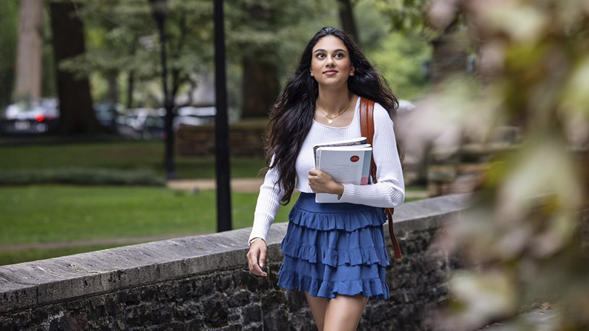 a student walks on a treed campus
