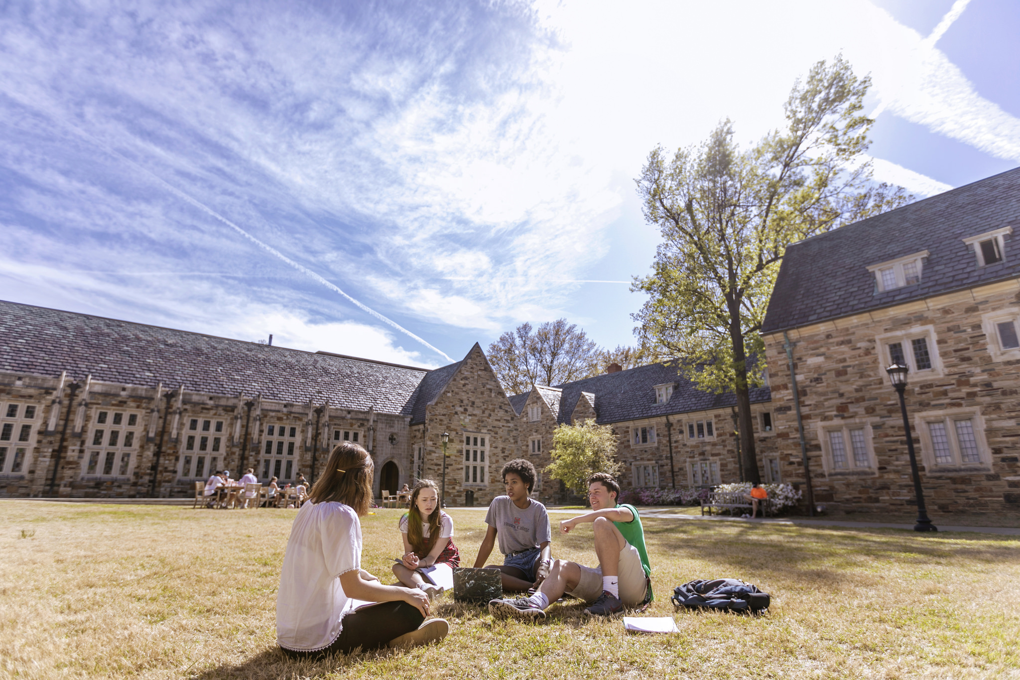 Students it on the grass outside a Rhodes building