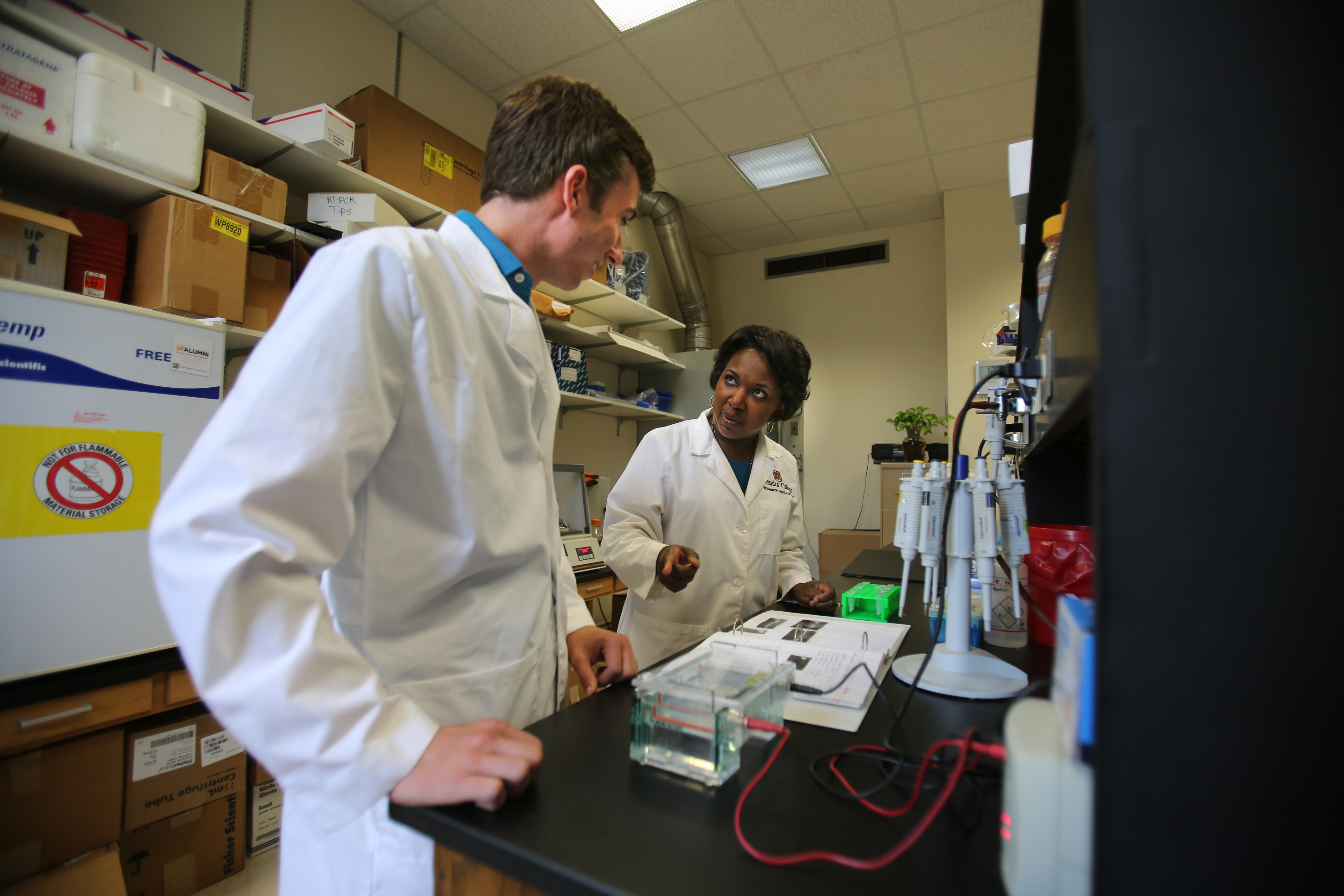 A professor in a laboratory setting explains results to a student standing next to her.