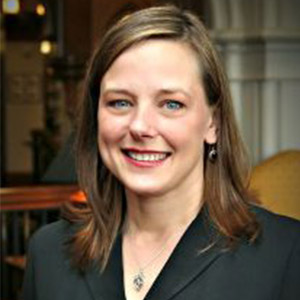 Woman in a black blazer with shoulder length brown hair.