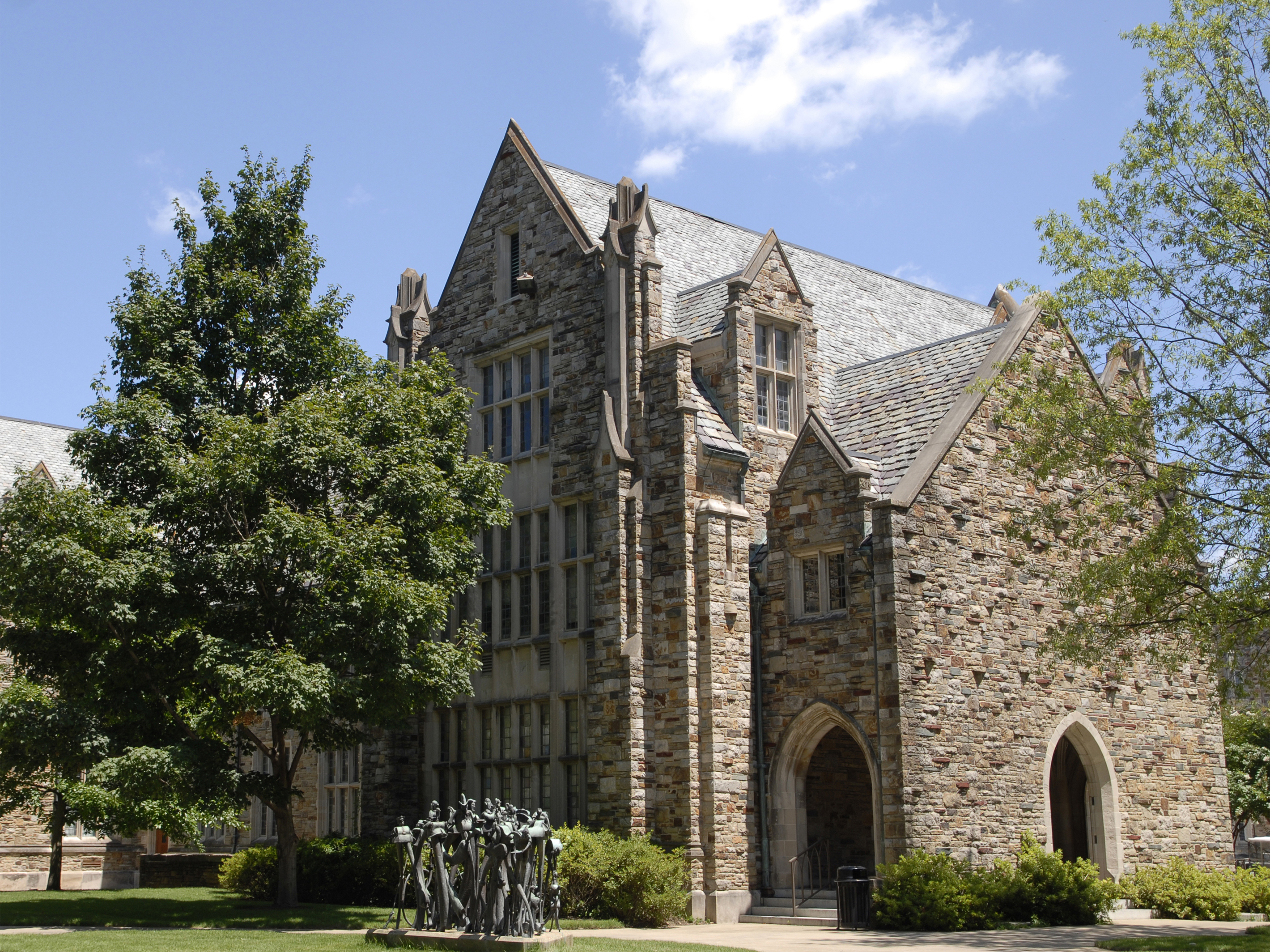 A stone edifice rises from behind some trees.