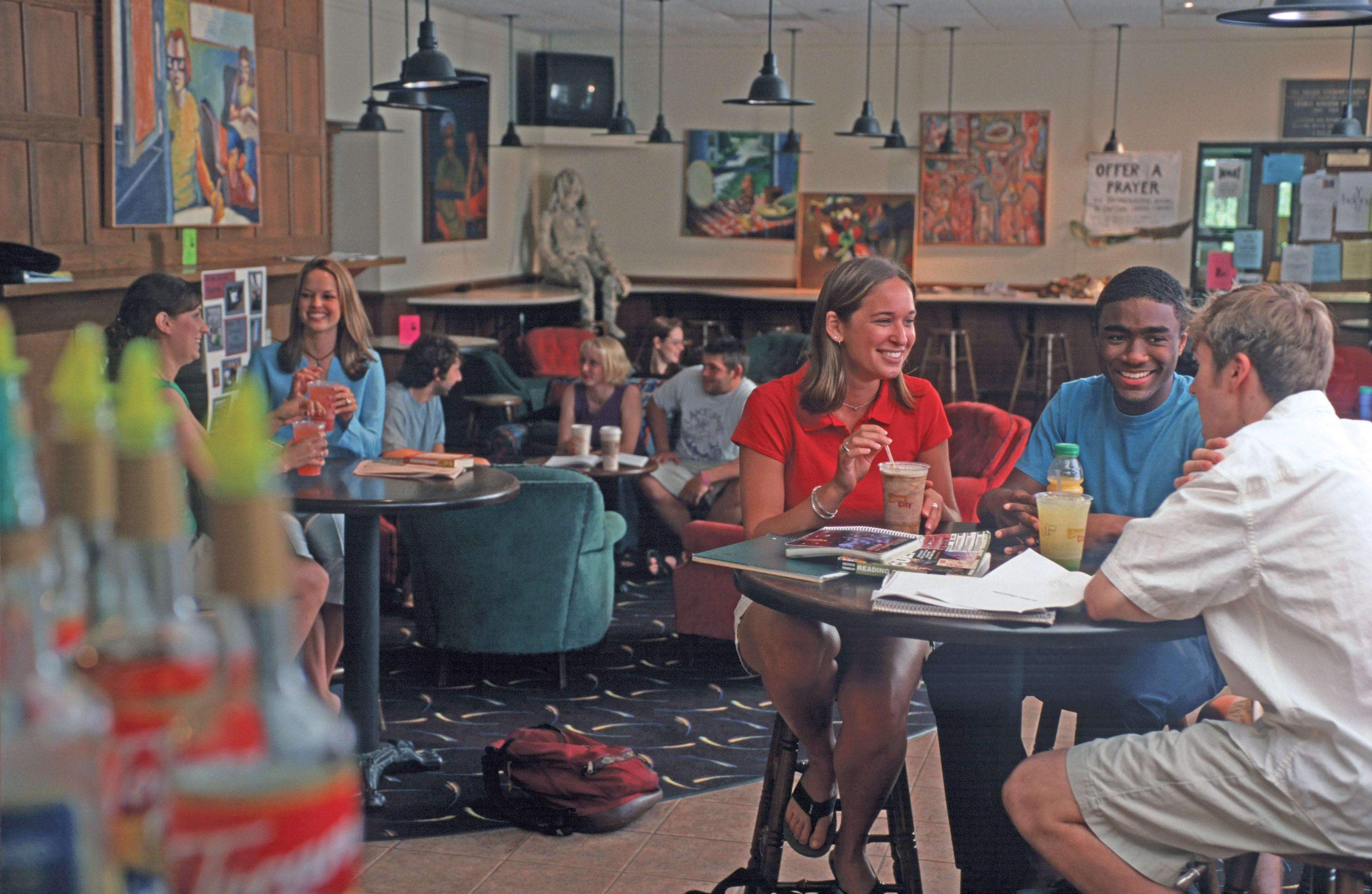 people sit at round tables with beverages in a cafe with lots of art