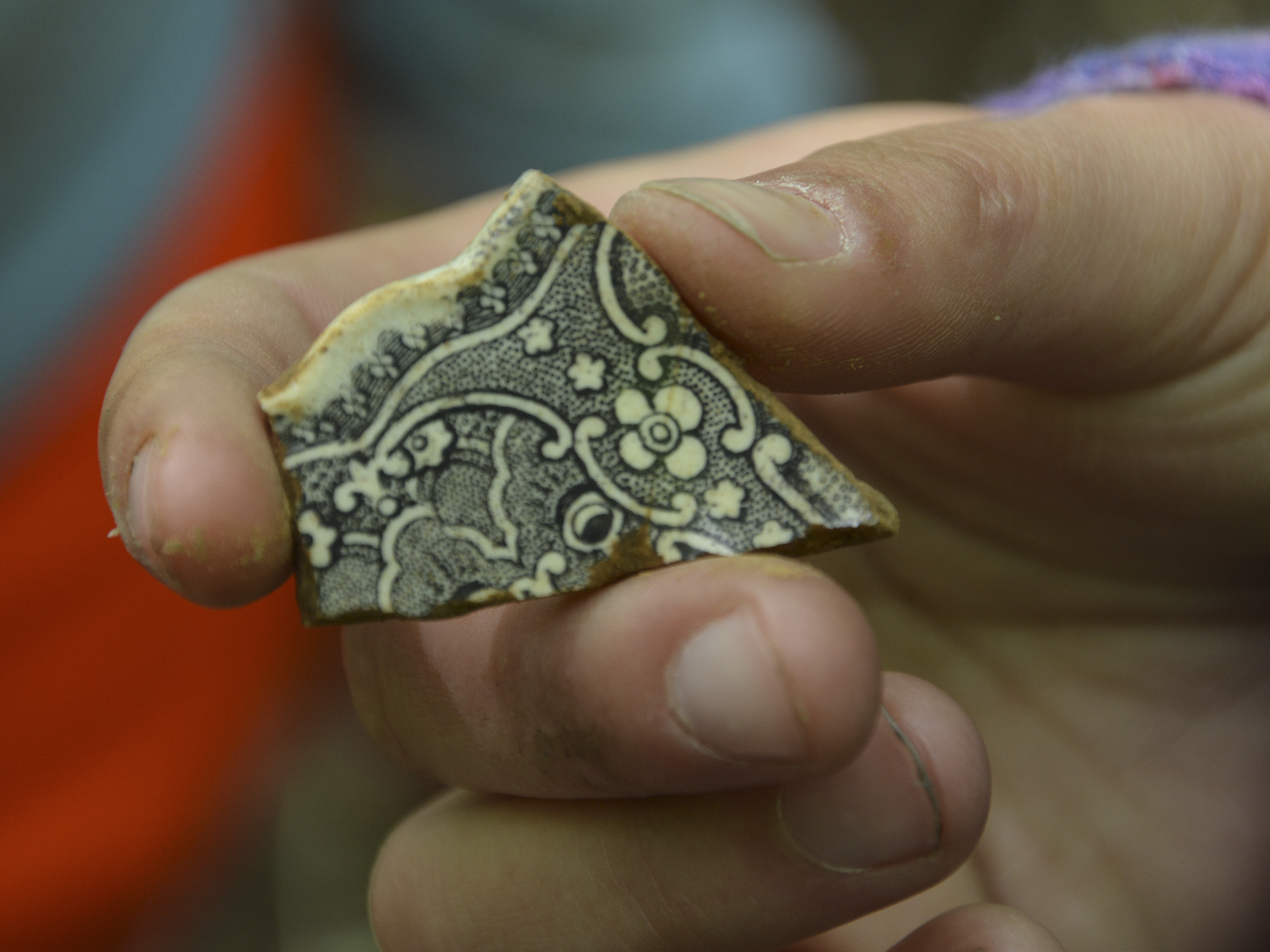 A fragment of a clay pot, intricately decorated with black line drawings.