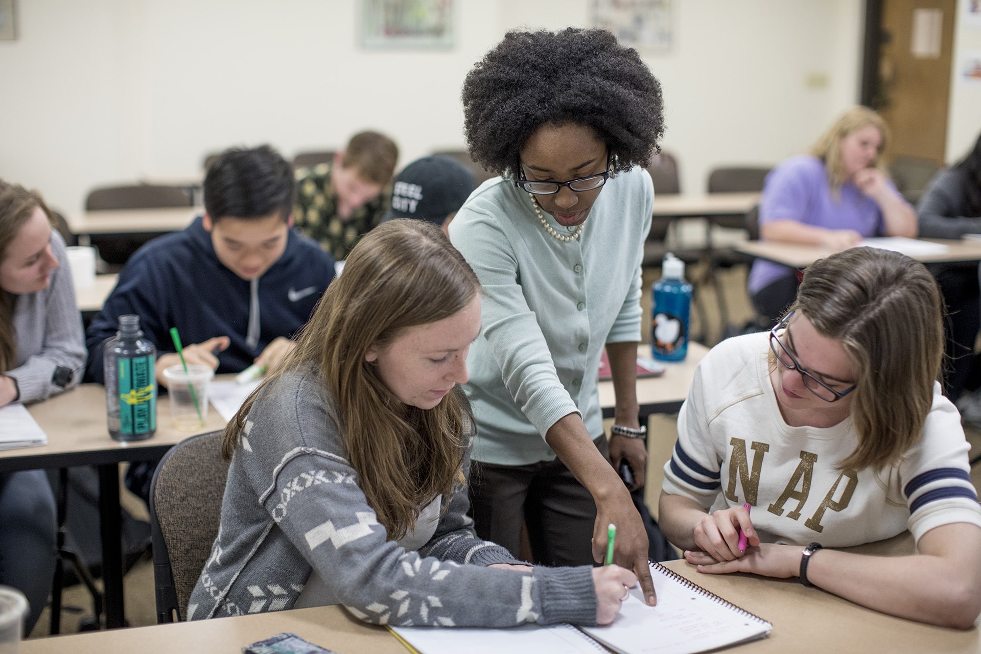 a professor pointing at a piece of paper while two students look.