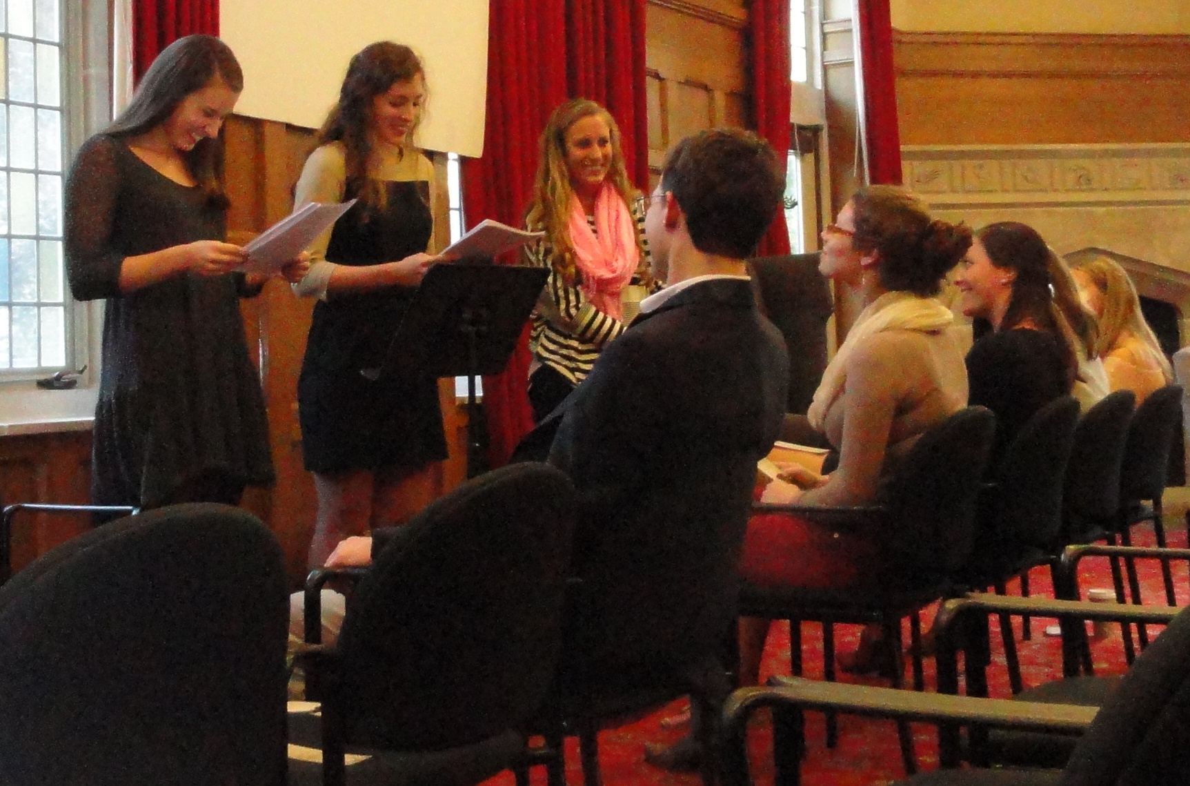 three women standing i front of seated students