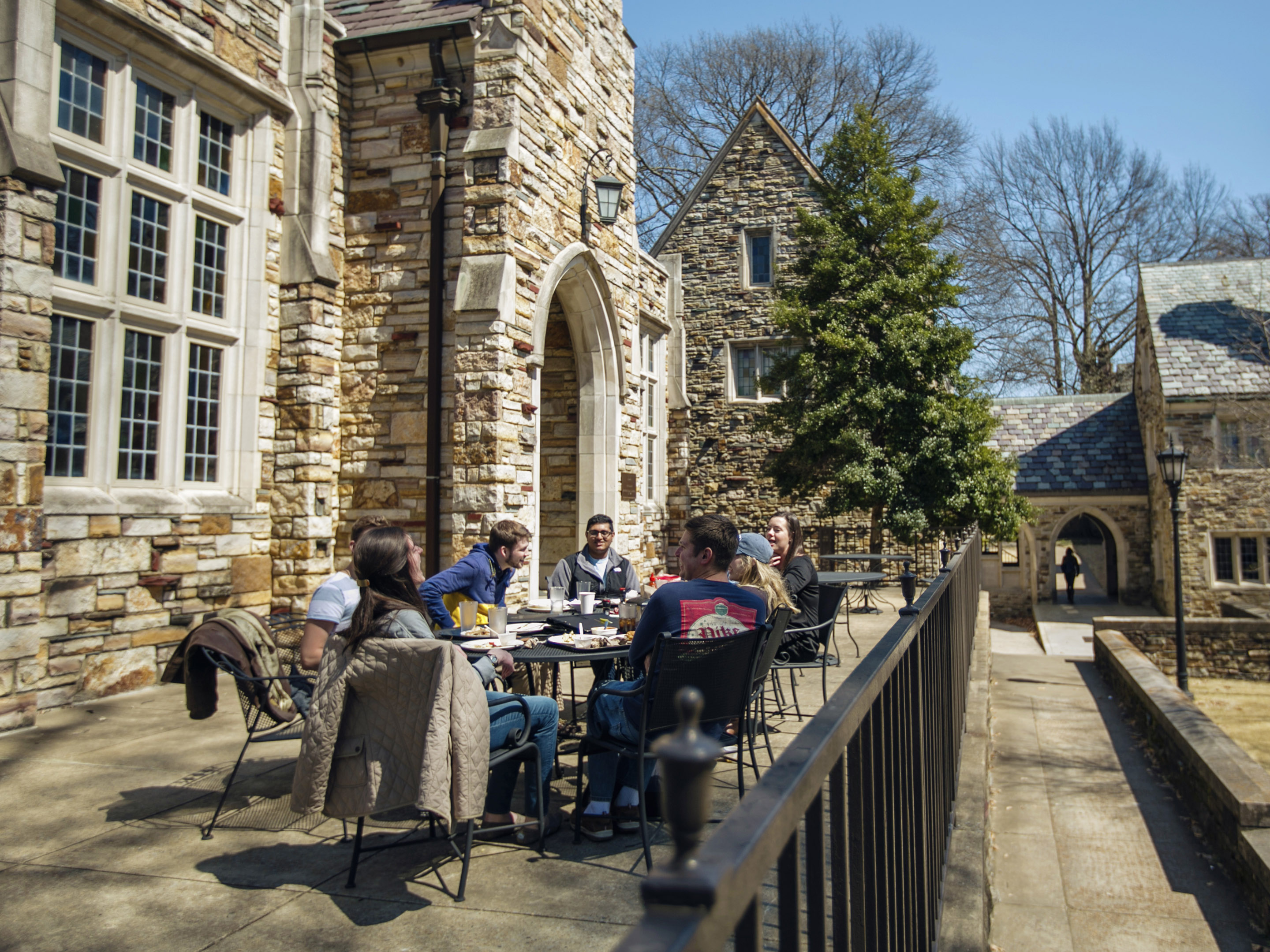 students on a patio of a gothic stone building
