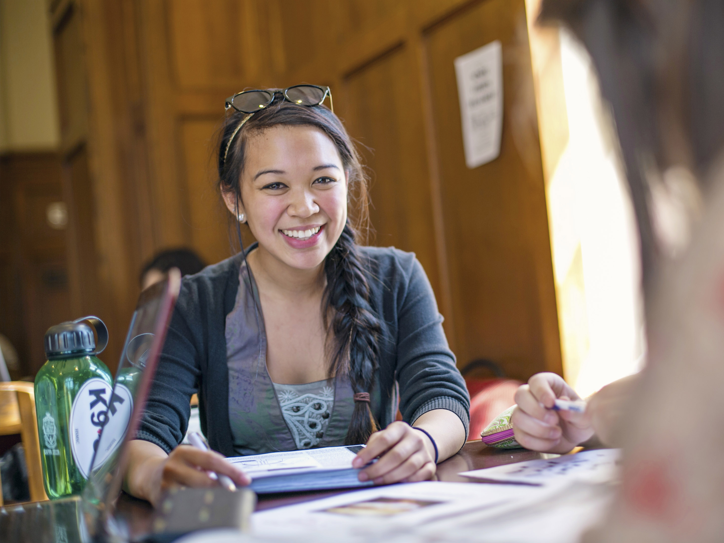 a student smiling and studying in the refectory