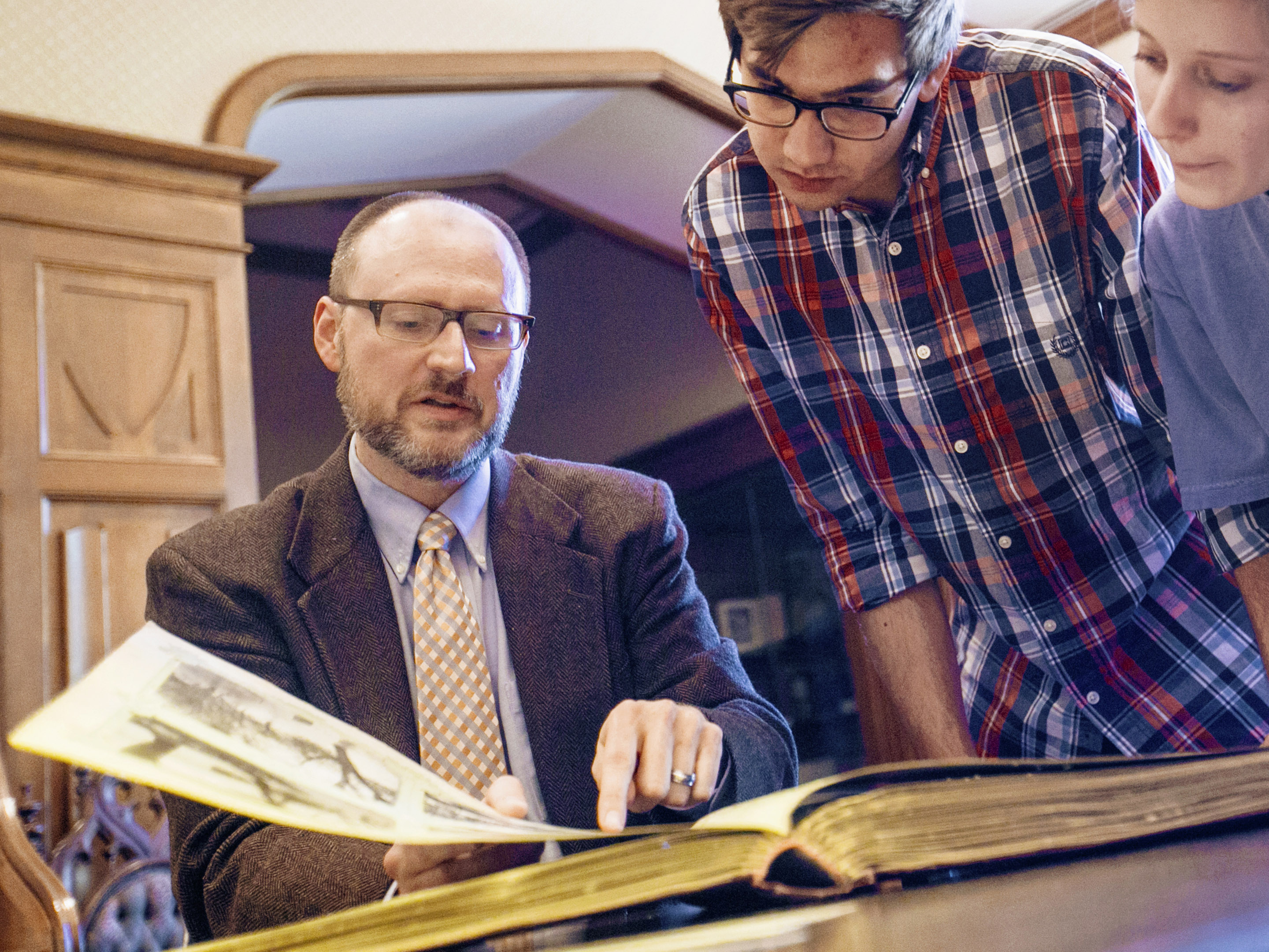 A professor and two students look at a manuscript