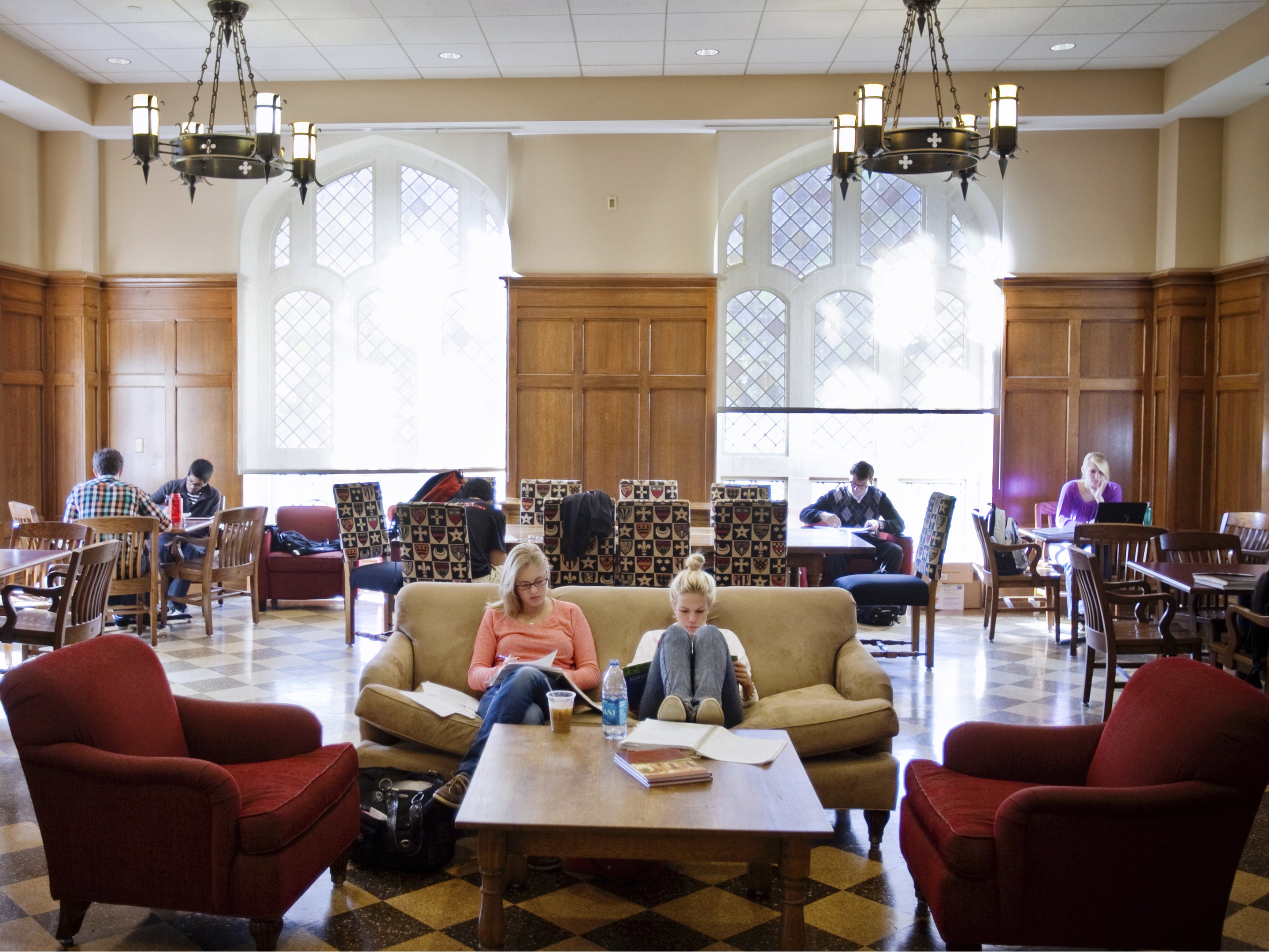 Two foregrounded students sit on a couch in the Middle Ground coffee shop