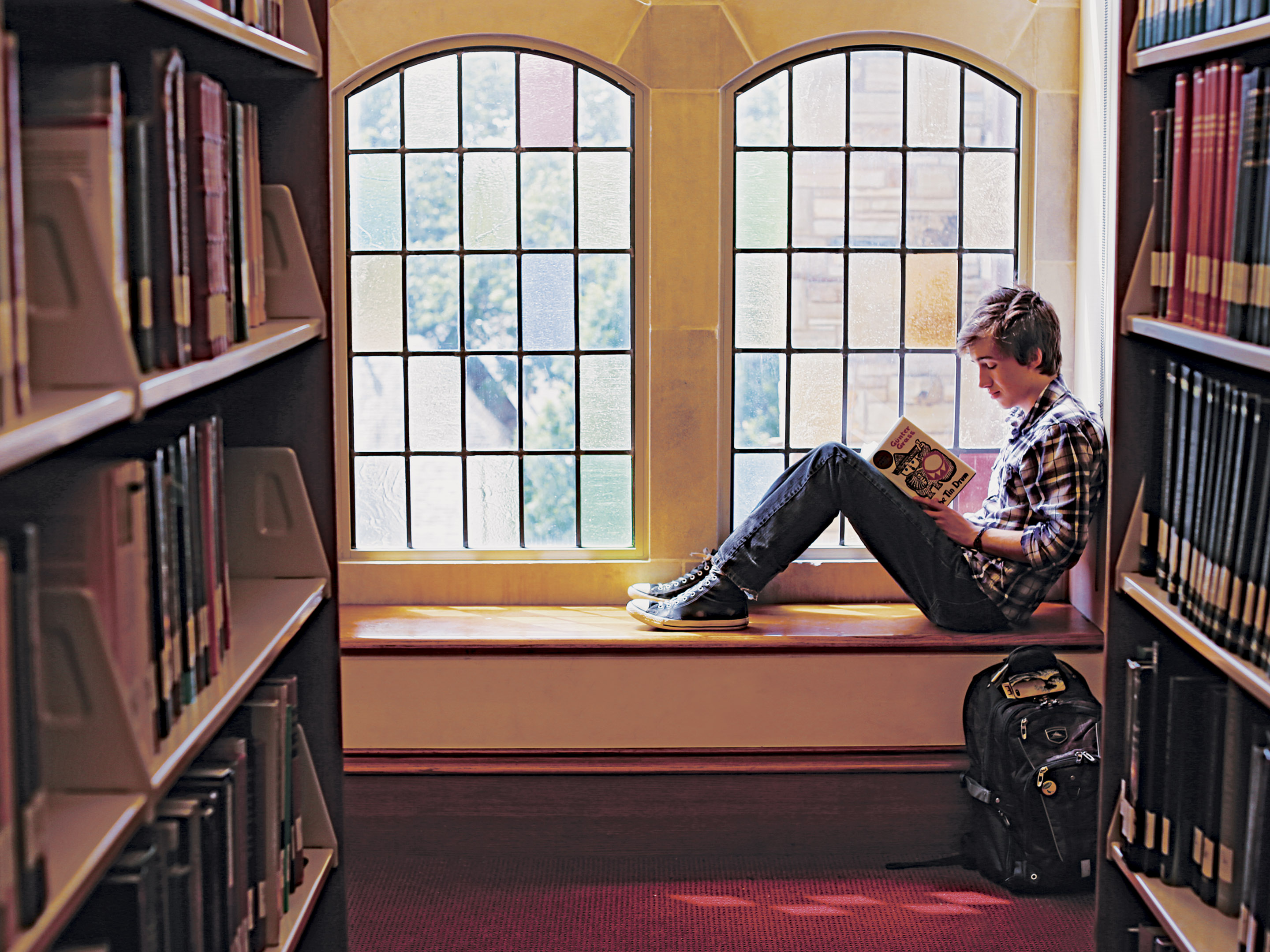 student reading a book in front of a window