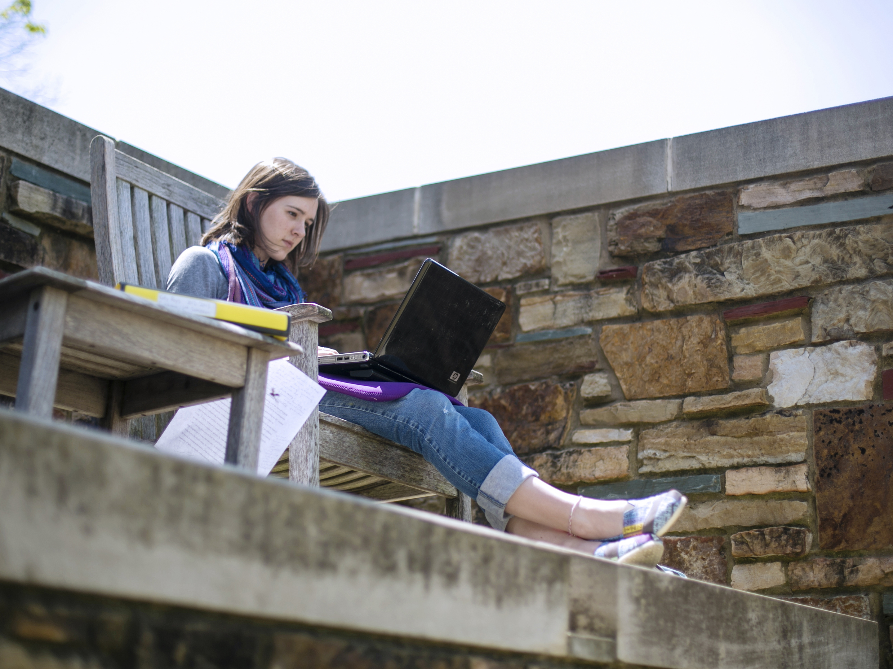 A student sitting on a bench with a laptop