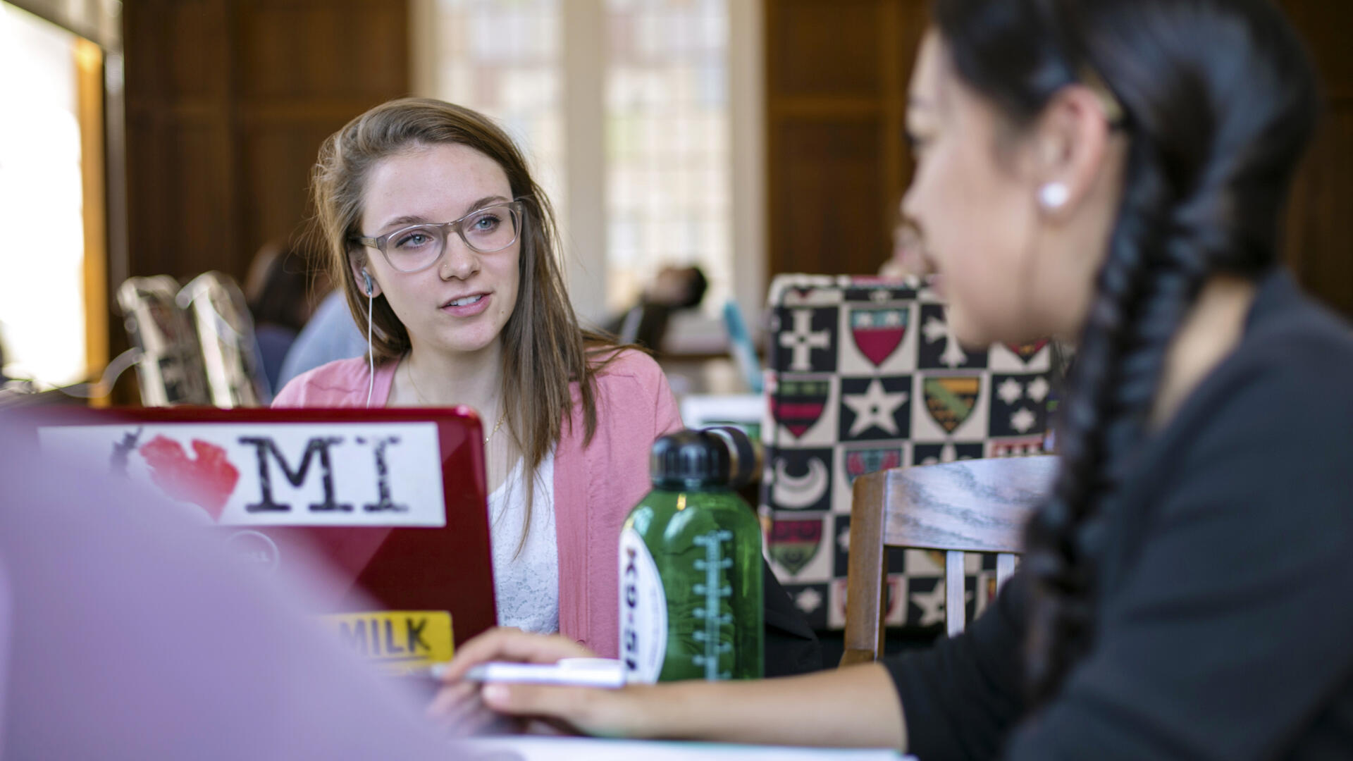 two students with a laptop talking around a table