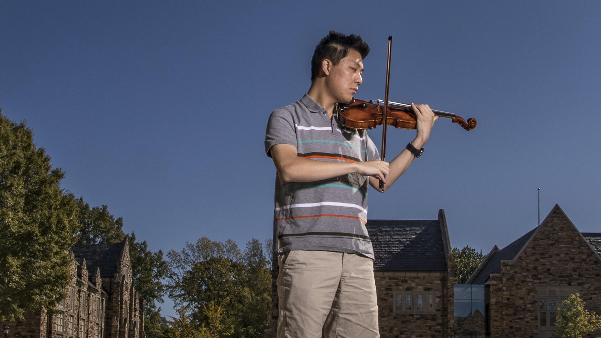 a young Asian man plays the violin
