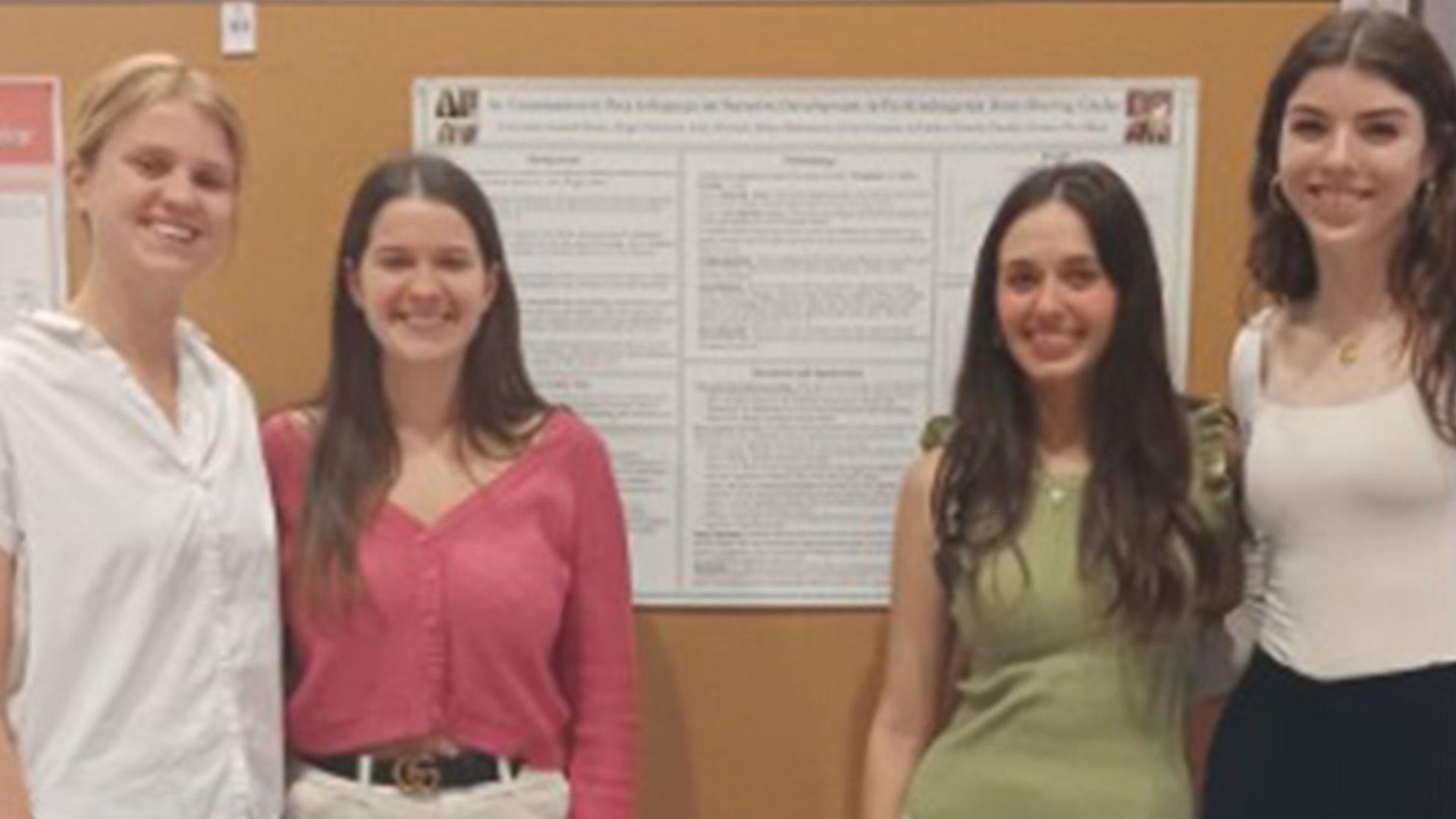 students pose in front of a research poster
