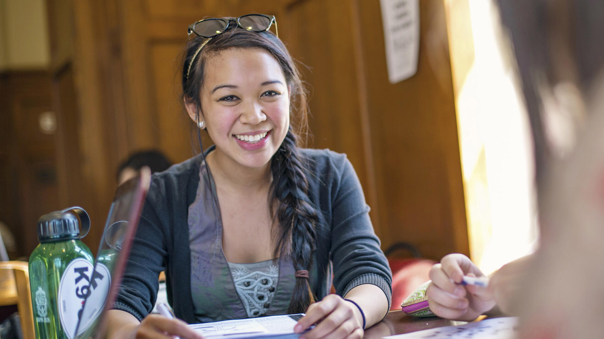 a student smiling and studying in the refectory
