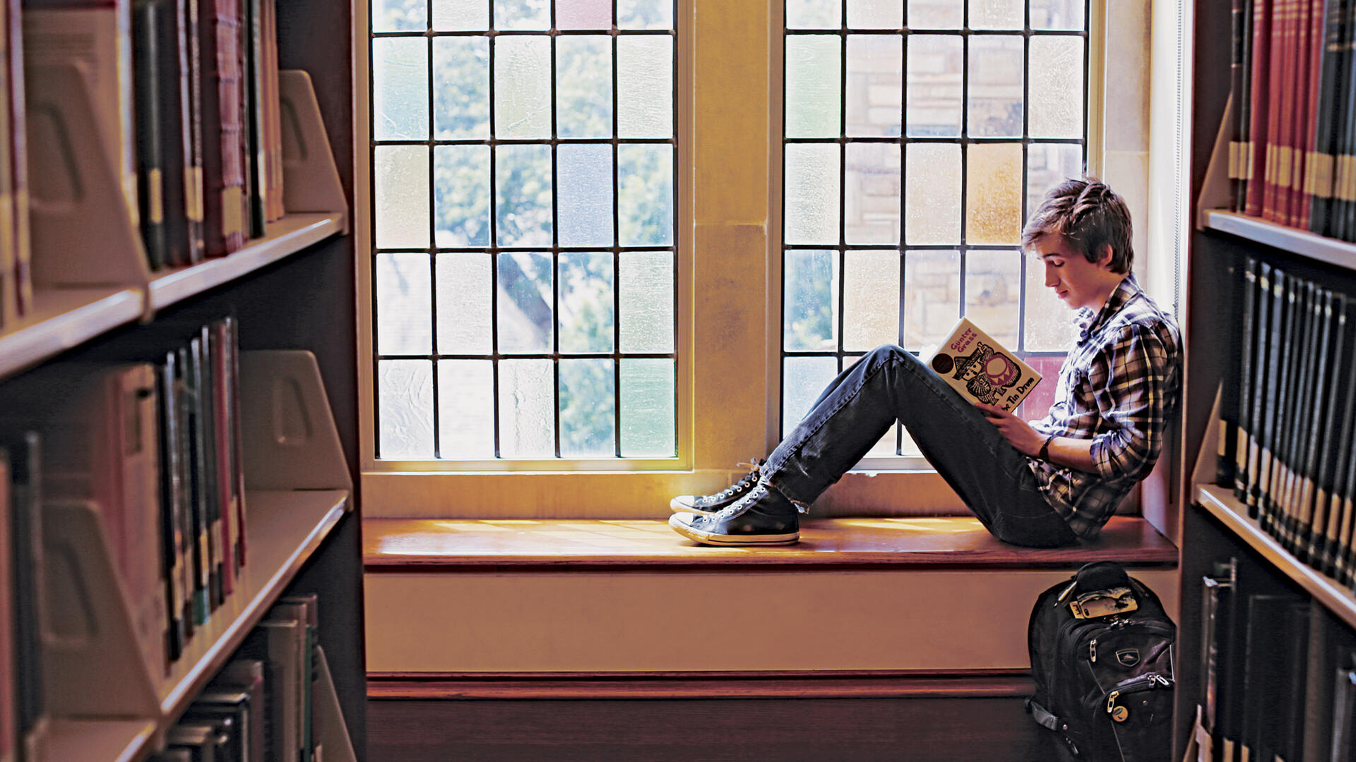 student reading a book in front of a window