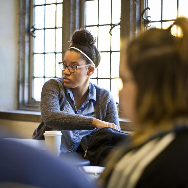 One student is surrounded by a circle of other students in a classroom