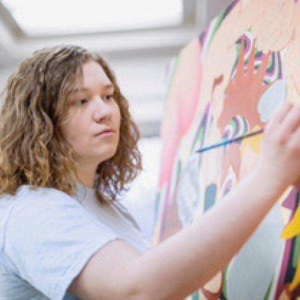 A young woman paints.