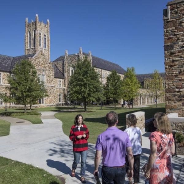 A student in a red and black rugby jersey leads a tour on a beautiful spring morning.