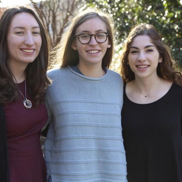 Three women stand together outside