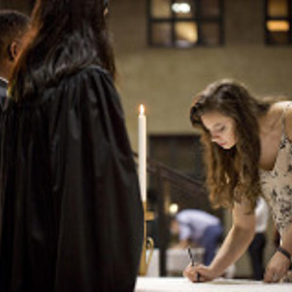 A young woman signs the Honor Code as members of the Honor Council look on.