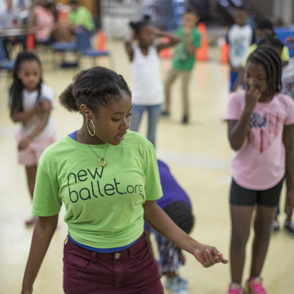 A female student shows dance steps to a group of children