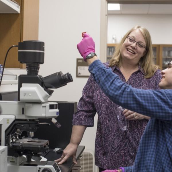 A professor and her student examine a lab specimen.