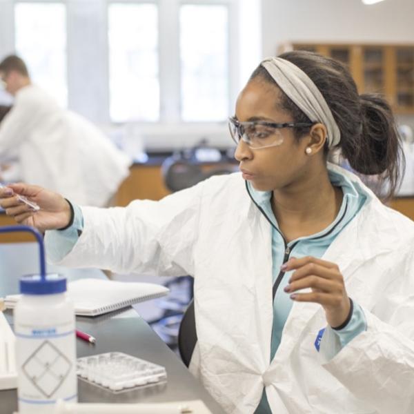 A student in a lab coat adjusts her equipment.
