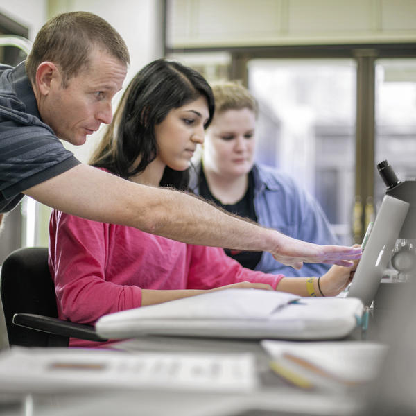 a professor working with a student points to a computer screen