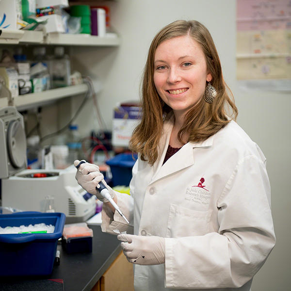 a student in a lab coat working with pipettes