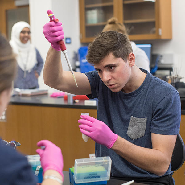 a college student measure liquid in a pipette